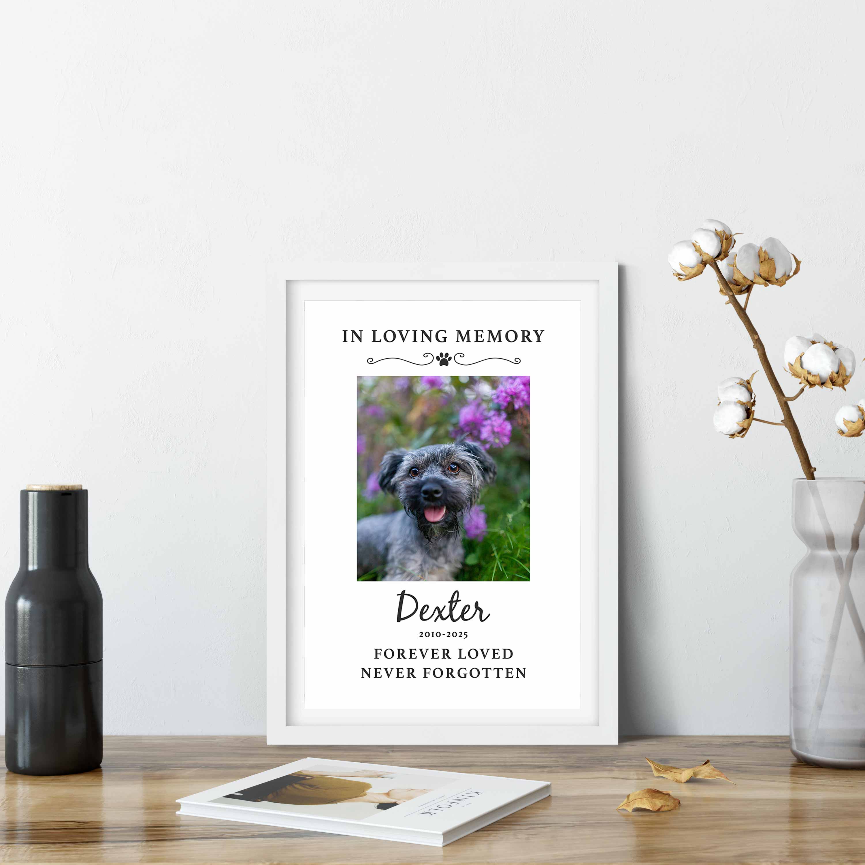Framed memorial print for a dog named Dexter with floral design on a table.